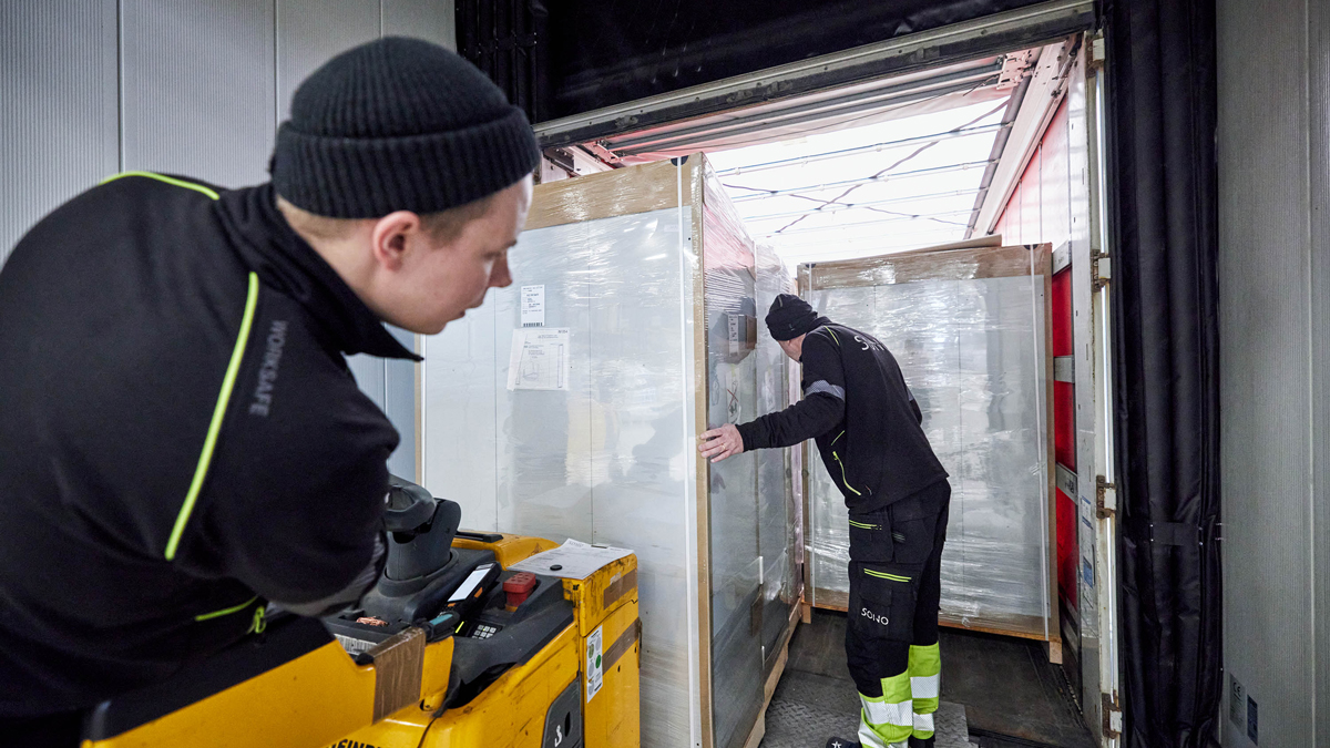 Bilden visar två anställda på vårt lager som förbereder en försändelse av garderobsskåp för lastning på en lastbil. De kan vara i färd med att packa och stapla skåpen på lastbilen, eller kanske kontrollerar de att varje skåp är korrekt märkt och förberett för leverans.